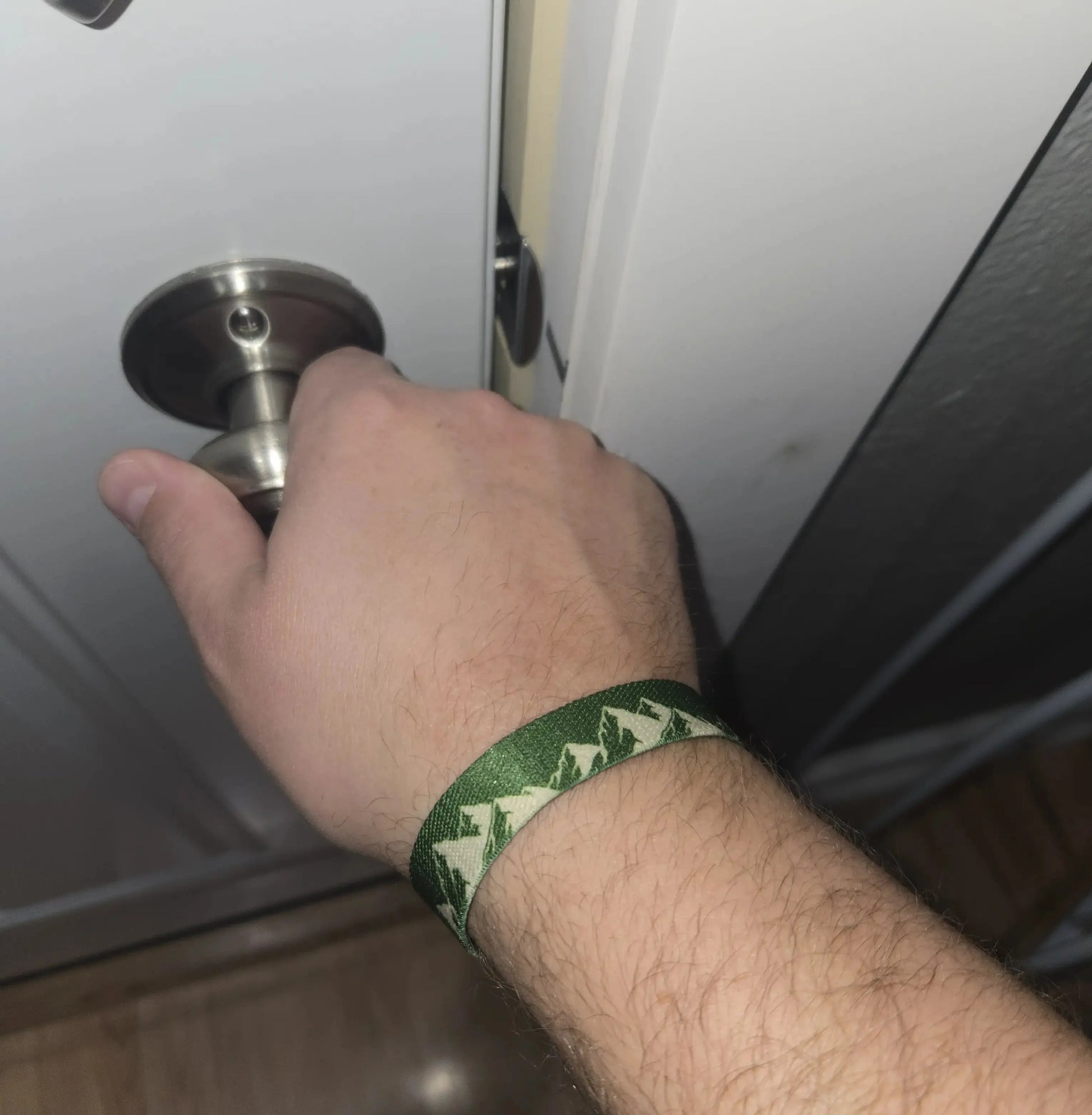 NFC wristband shown on arm. Green wristband with mountain design and Verse On Tap label on a white background, reverse side has Topography lines.