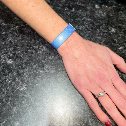 Wristband shown worn on wrist. Reversible Christian NFC elastic wristband with a star-filled night sky design on one side.