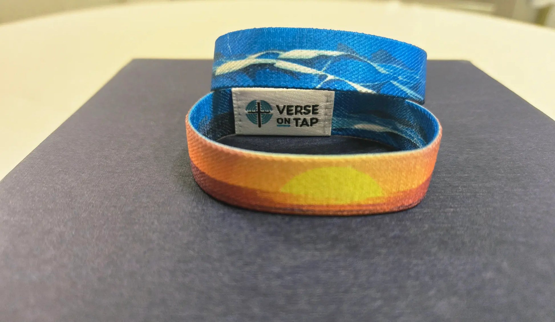 Reversible bracelet. Peace Be Still NFC elastic wristband showing a calming sunset design on one side and the other has a blue stormy ocean pattern inspired by Mark 4:39.