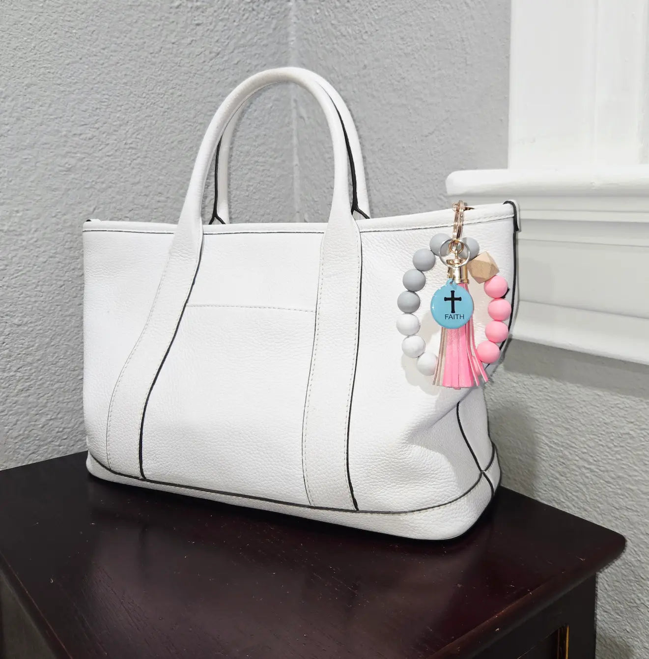 NFC keychain shown on white purse. Teal NFC keychain with black cross and "FAITH" black text.