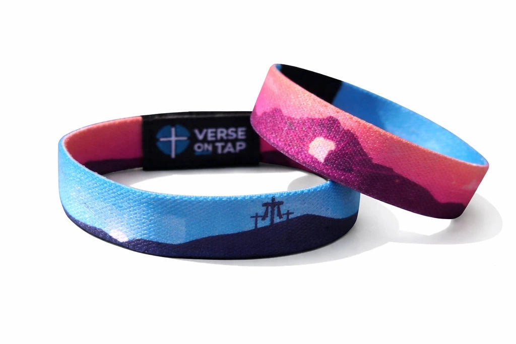 Two elastic NFC wristbands with blue, pink, and purple mountain design and small cross symbols, shown on a white background.