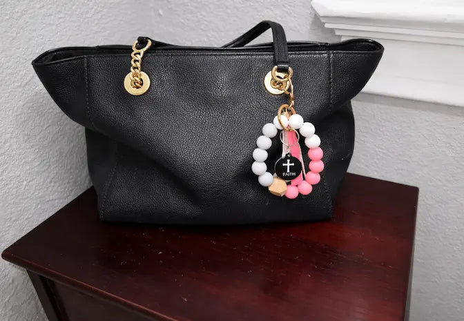 NFC keychain shown on black purse. Black NFC keychain with white cross and "FAITH" white text.