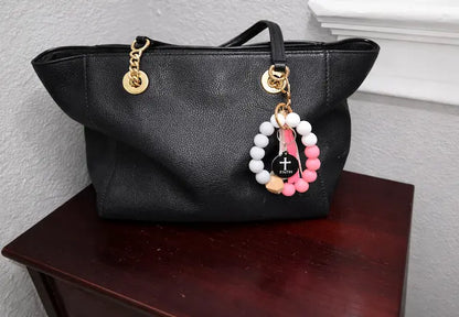 NFC keychain shown on black purse. Black NFC keychain with white cross and "FAITH" white text.